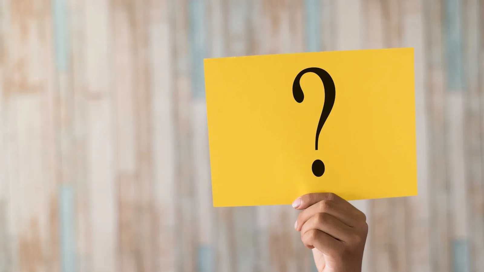 A hand holding a question mark sign