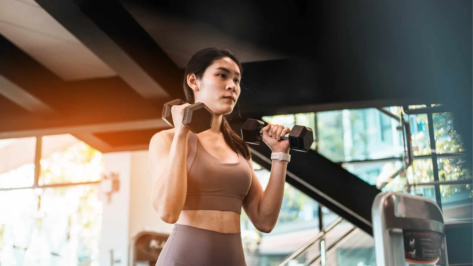 Young woman exercising with dumbbells in a backyard gym shed