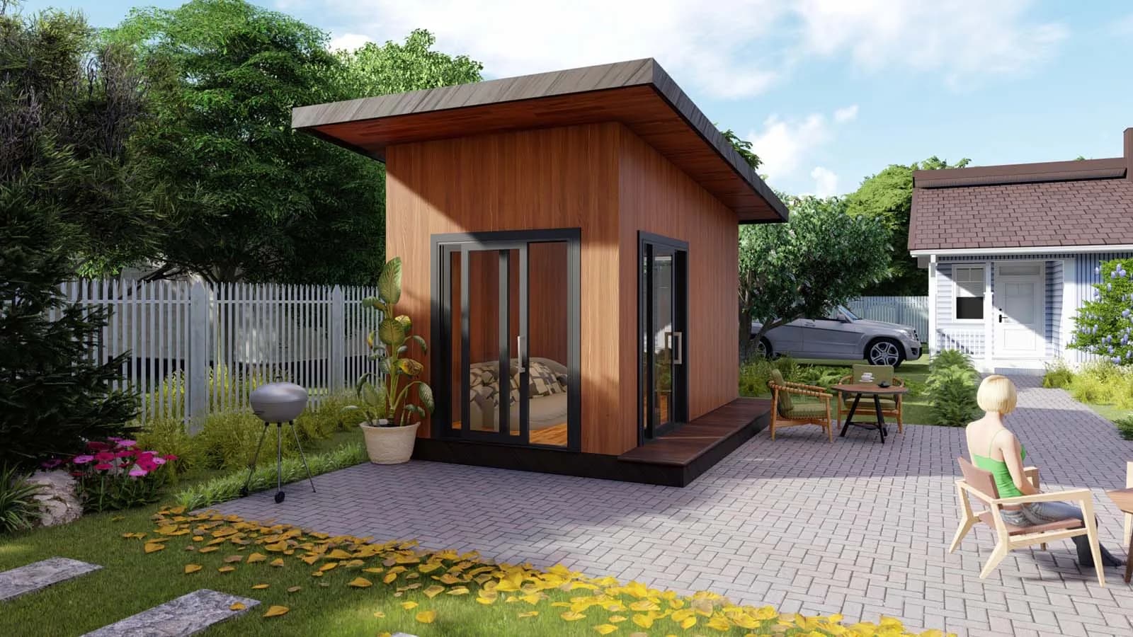 Wood-clad backyard office with sliding glass doors and a small deck in an autumn garden