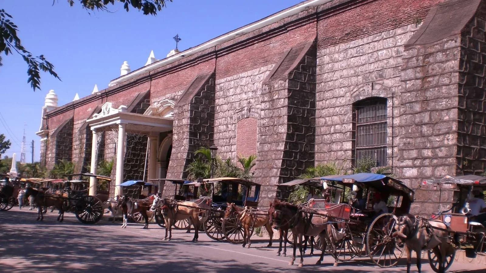 Historic carriage houses with horse-drawn carriages parked nearby
