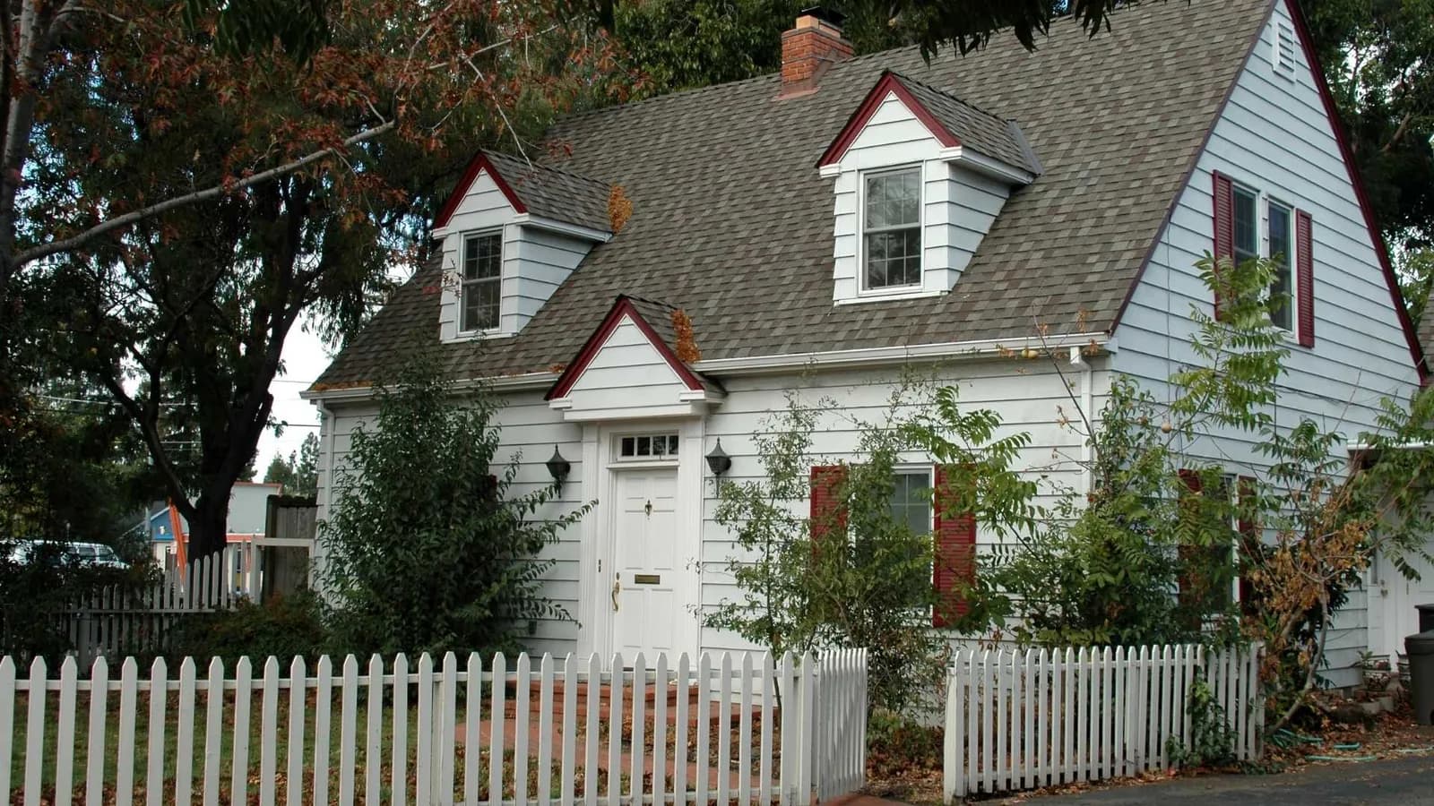 Two-story carriage house with dormers, white siding and red accents